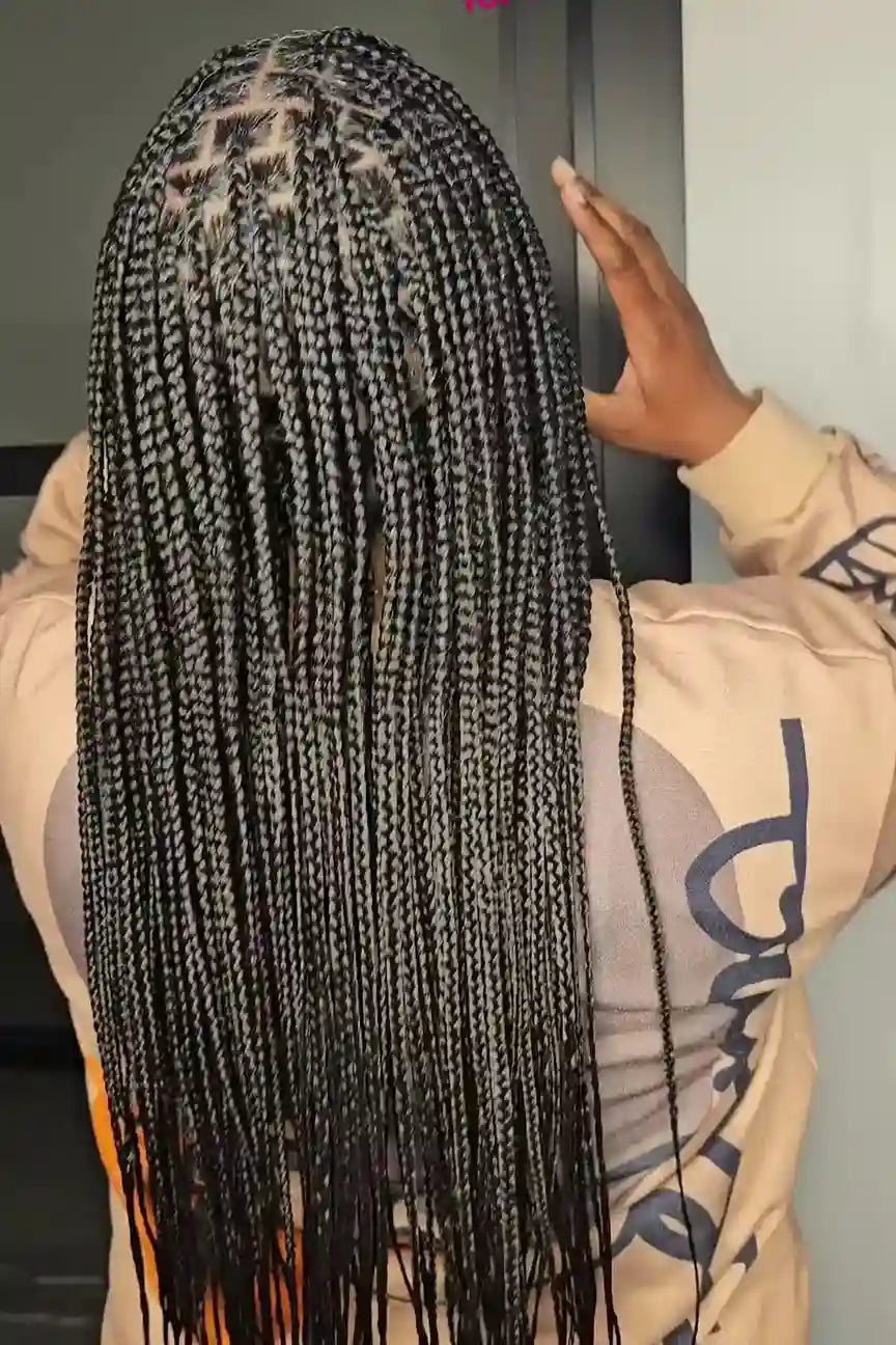 Person with long braided hair wearing a beige jacket.