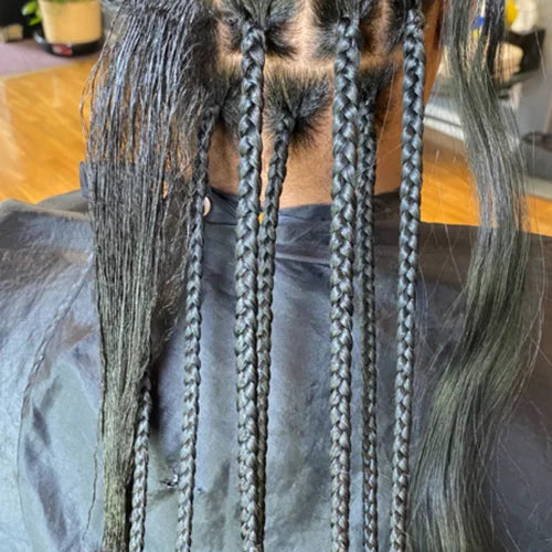 Close-up of braided hair extensions on a person wearing a gray shirt.