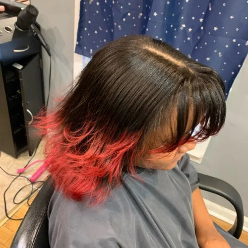 Person with black hair transitioning to red at the ends in a salon setting.