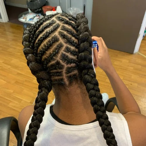 Person with intricately braided hair in a room with wooden flooring.