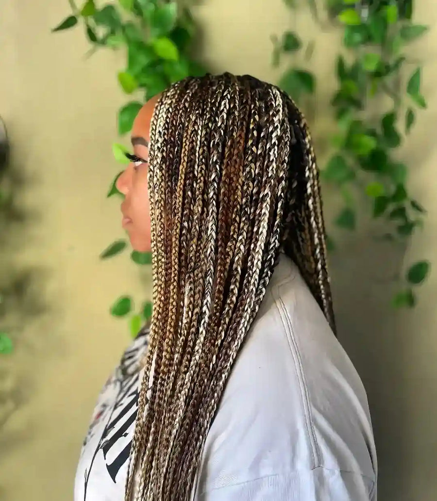 Person with braided hair against a green leafy background