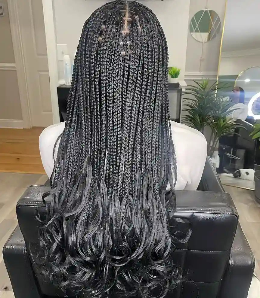 Person with braided hair sitting in a salon chair.