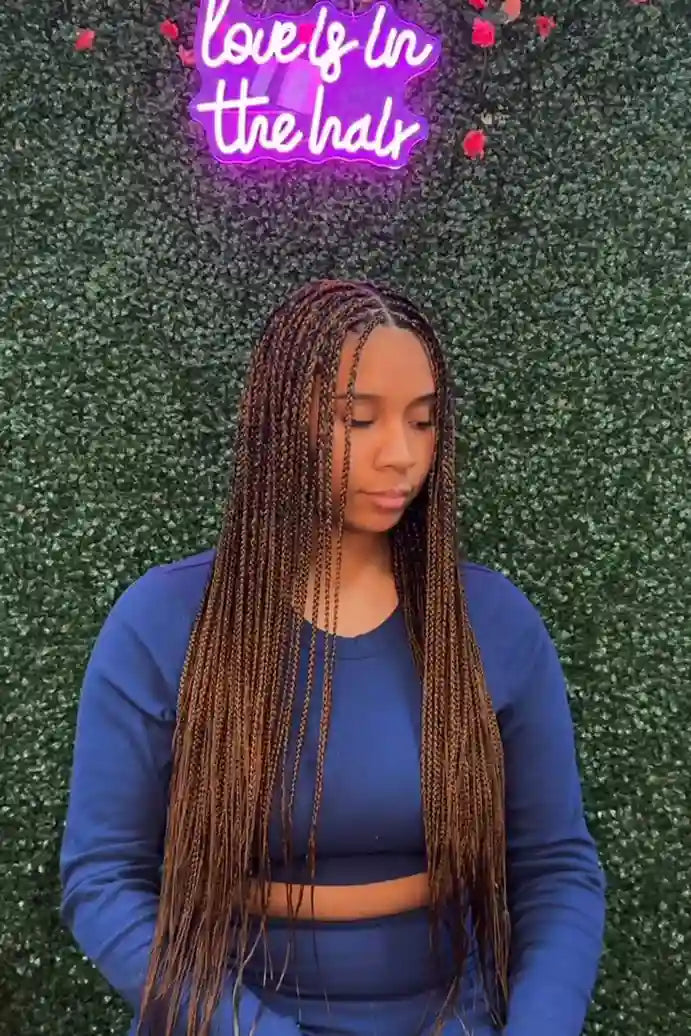 Person with long braided hair wearing a blue outfit against a green textured background with 'Love is in the hair' text.