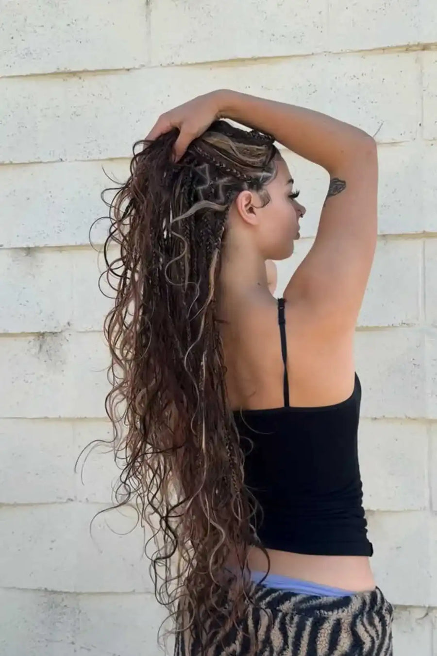 Person with long, styled hair against a light-colored wall