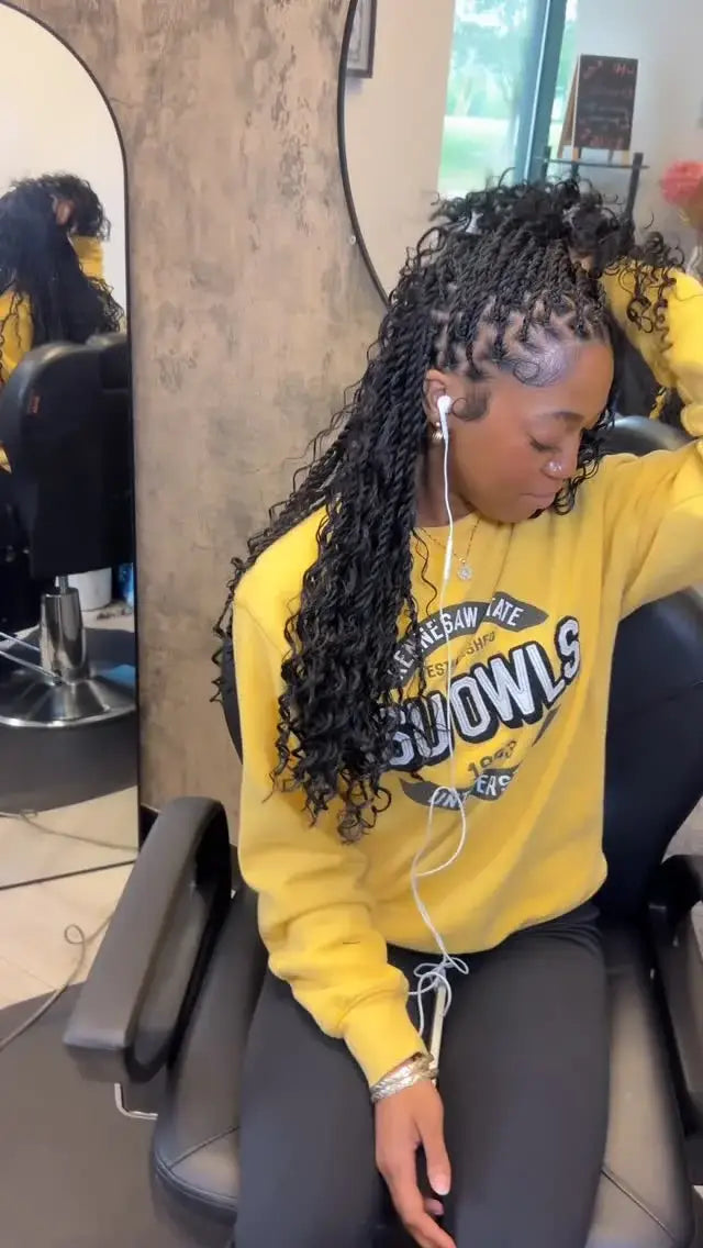 Woman in a yellow sweatshirt sitting in a salon chair with headphones on.