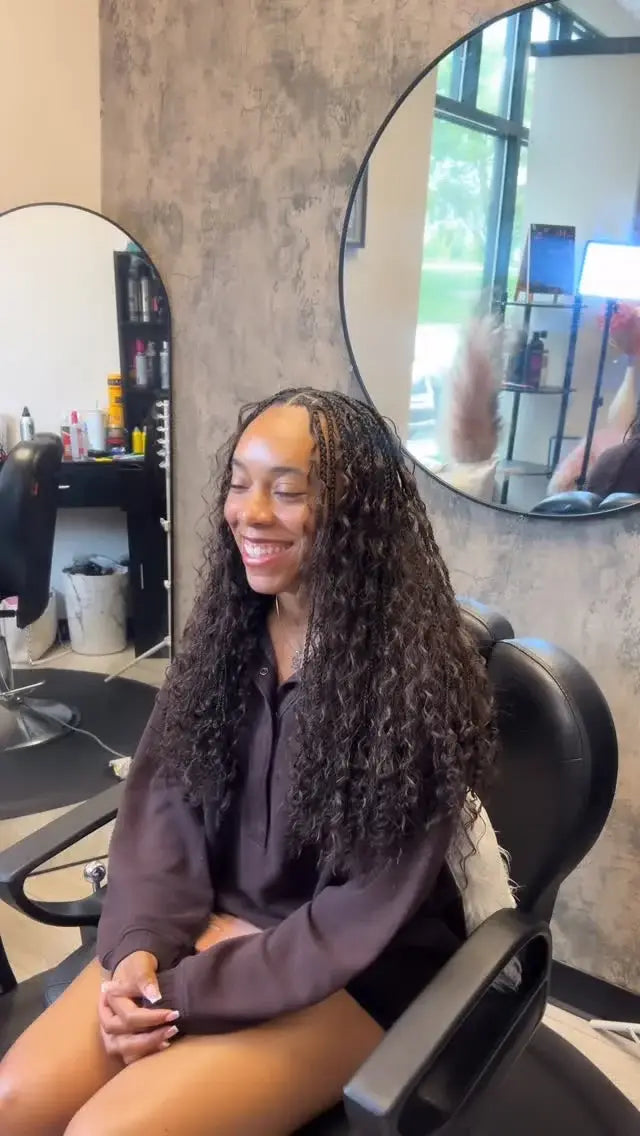 Woman with long, styled hair sitting in a salon chair.