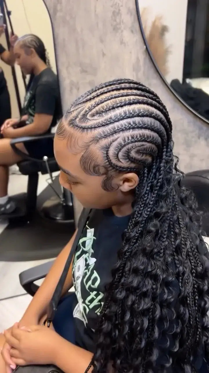 Person with intricate braided hair sitting in a salon chair.