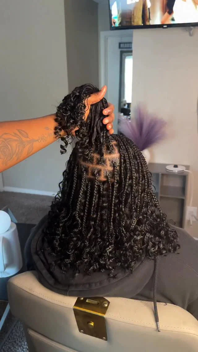 Person holding a wig with braided hair in a living room setting.