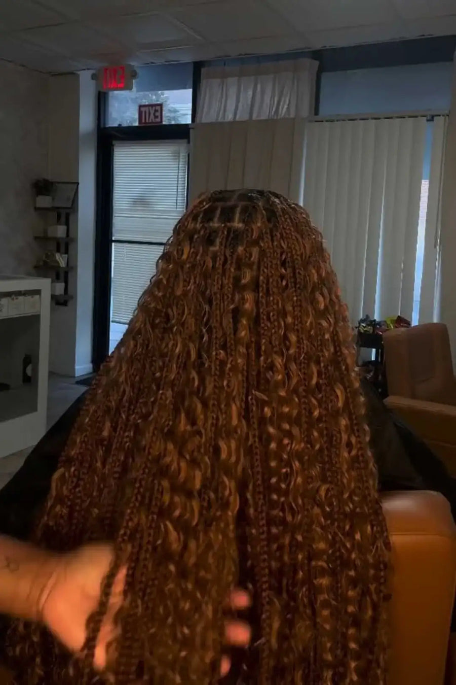 Person holding a large bundle of braided hair extensions indoors.