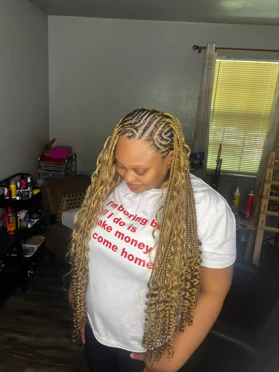 Person with braided hair wearing a white t-shirt in a room with furniture and decor.