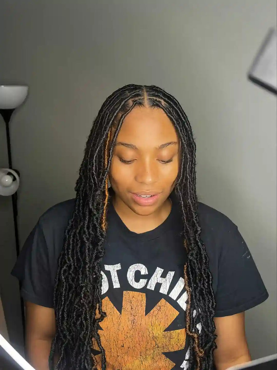 Person with braided hair wearing a black t-shirt with a graphic design.
