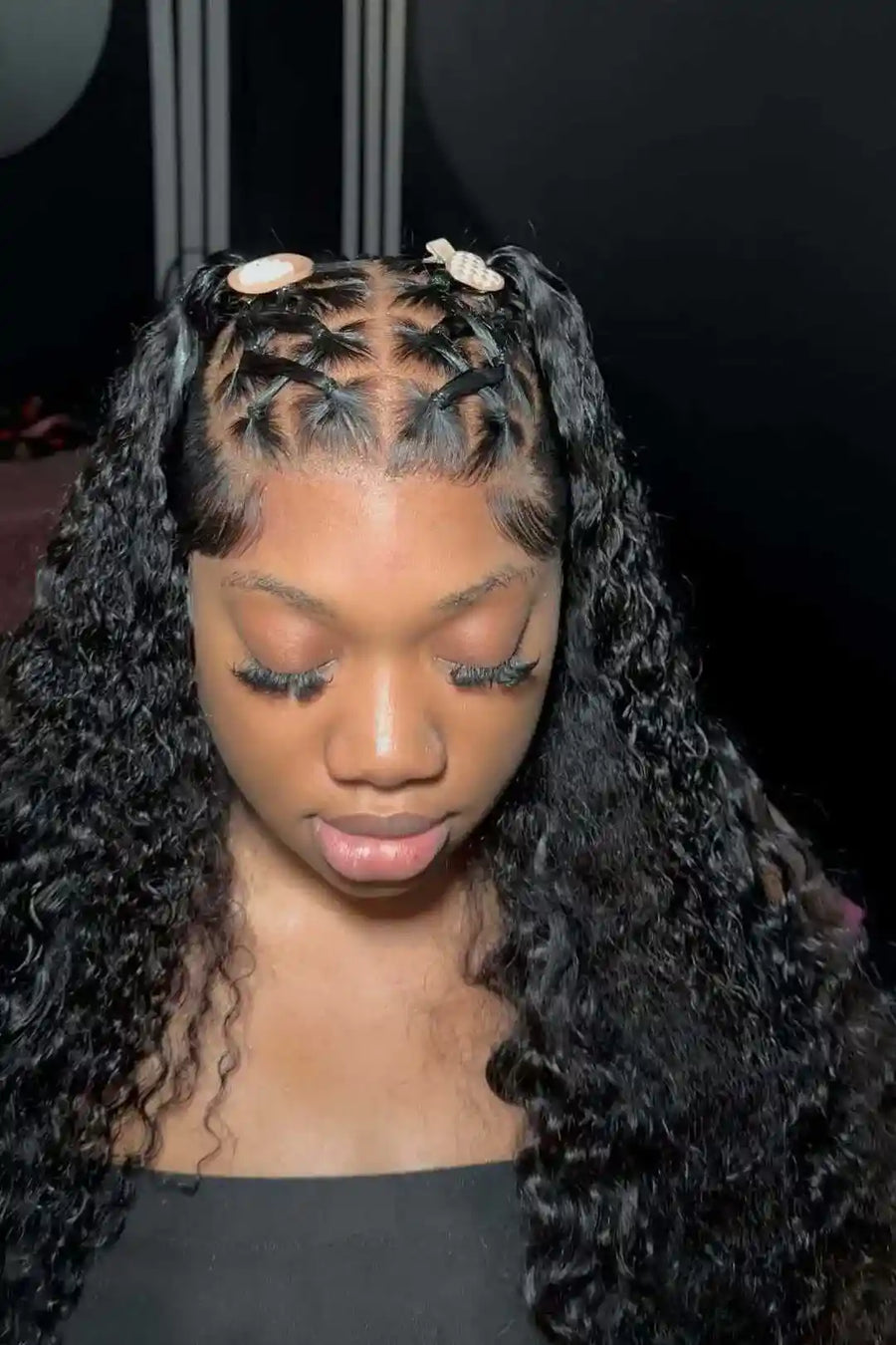 Woman with styled hair featuring braids and curls against a dark background