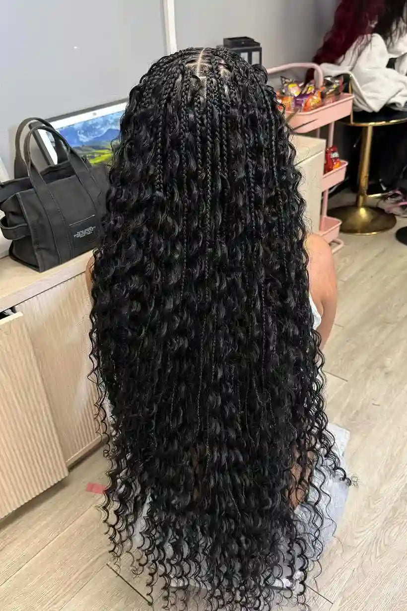 Person with long, curly black hair in a room with furniture and decor.