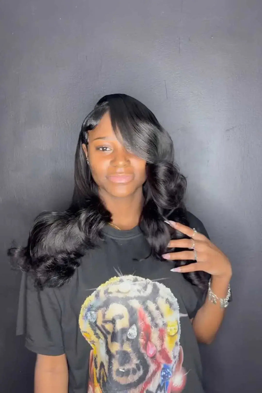 Person with styled hair wearing a graphic t-shirt against a dark background