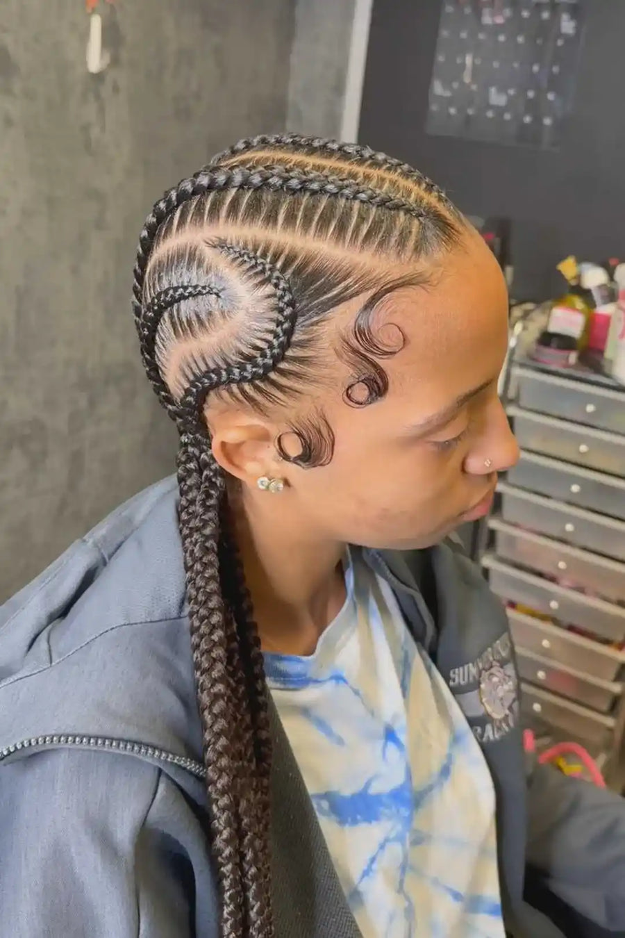 Person with intricate braided hairstyle in a salon setting