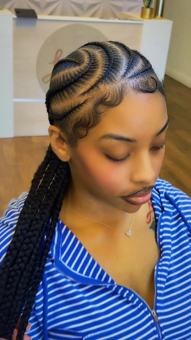 Woman with styled braids wearing a blue and white striped top indoors.