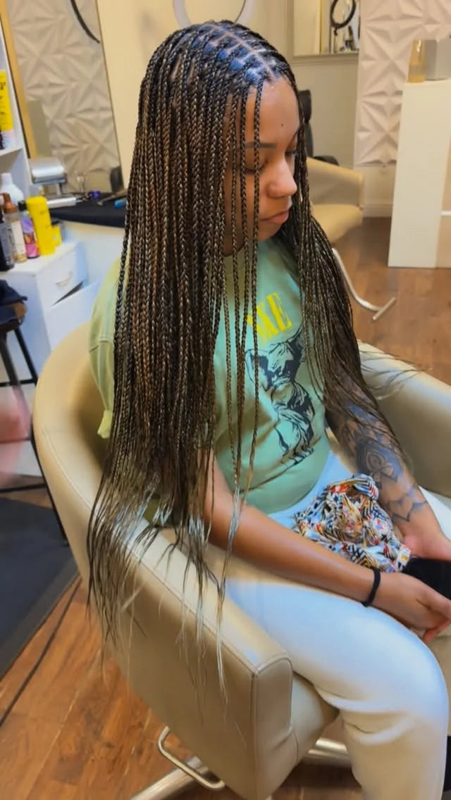Person with braided hair sitting in a salon chair.