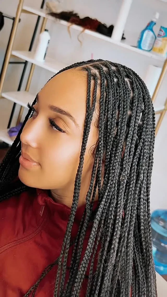 Person with braided hair in a room with shelves and bottles.