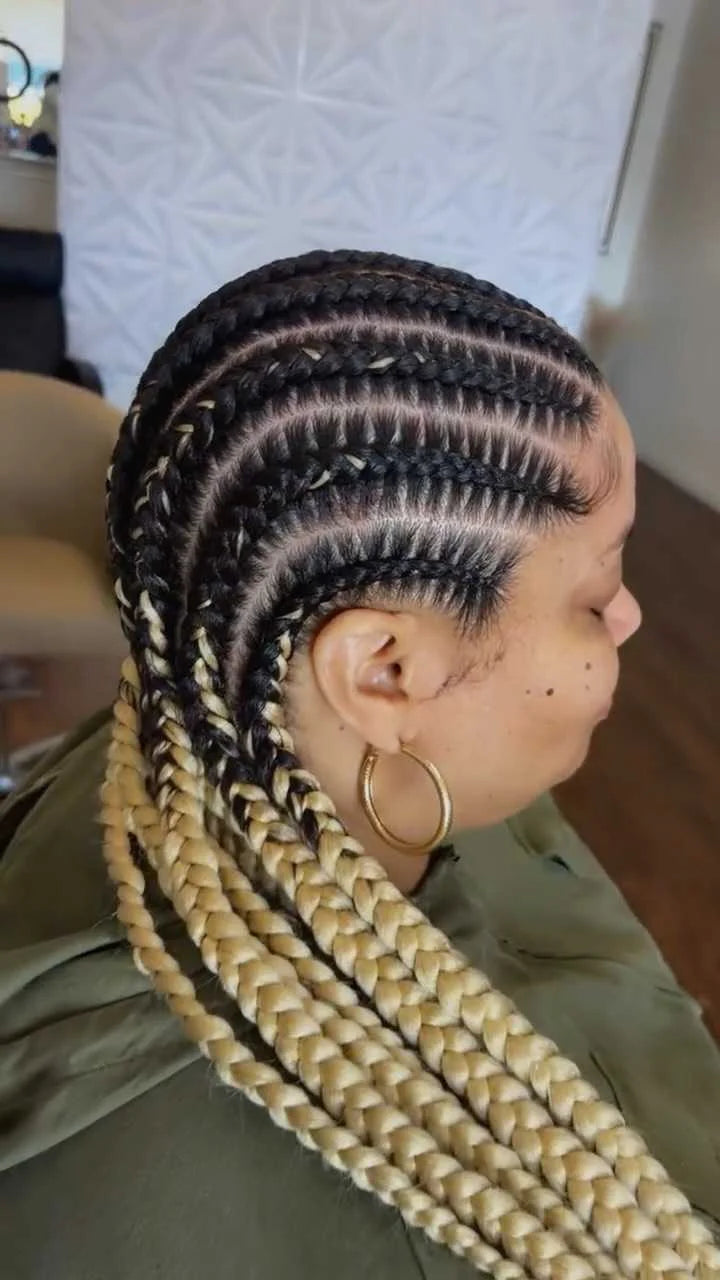 Person with braided hair styled in cornrows, wearing a gold hoop earring.