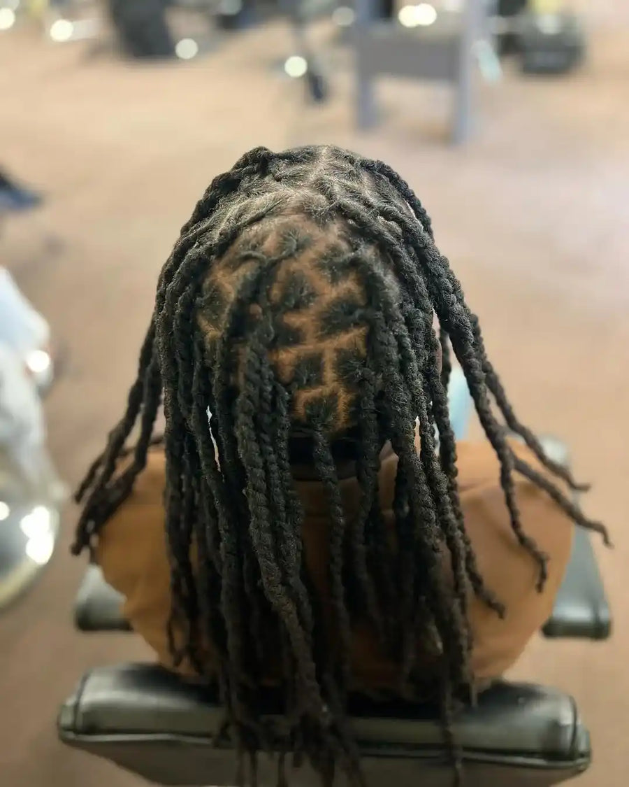 Person with styled dreadlocks sitting in a chair, blurred background