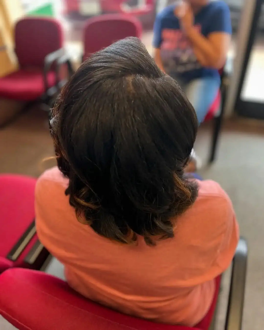 Person with braided hair sitting on a red chair in a room with blurred background