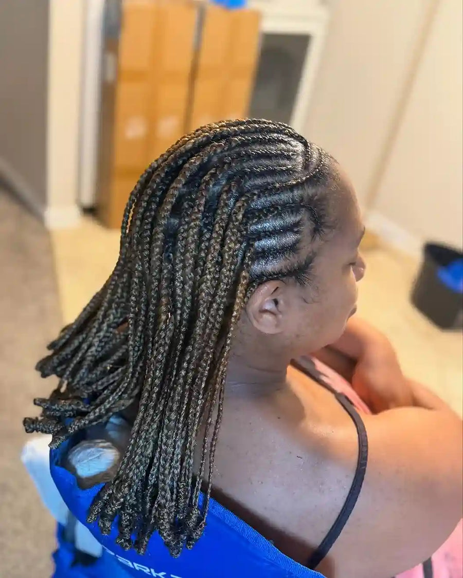 Person with braided hair sitting on a chair indoors