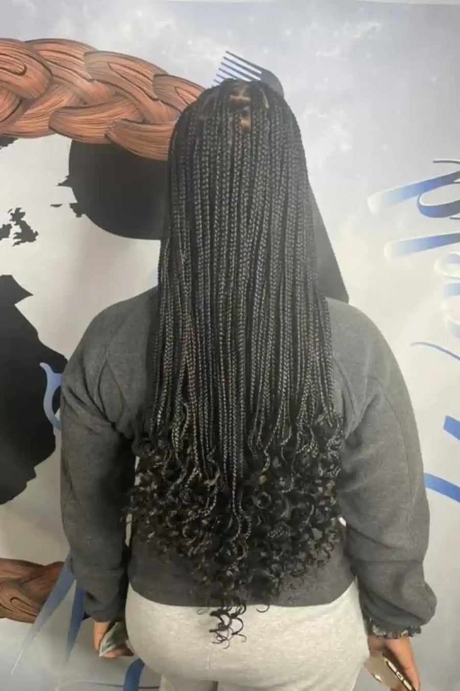 Person with long braided hair against a mural background