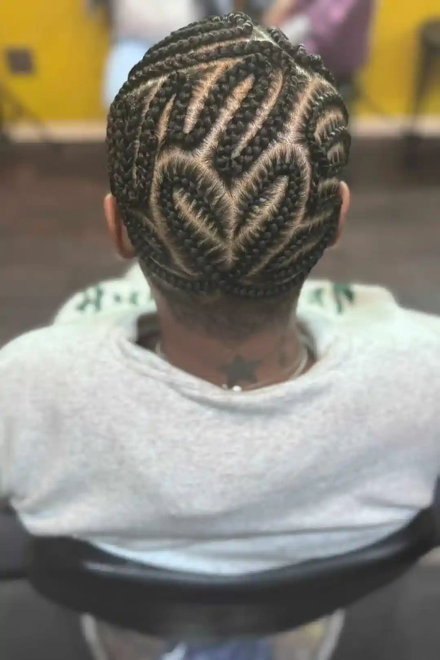Person with intricately braided hair sitting in a chair.