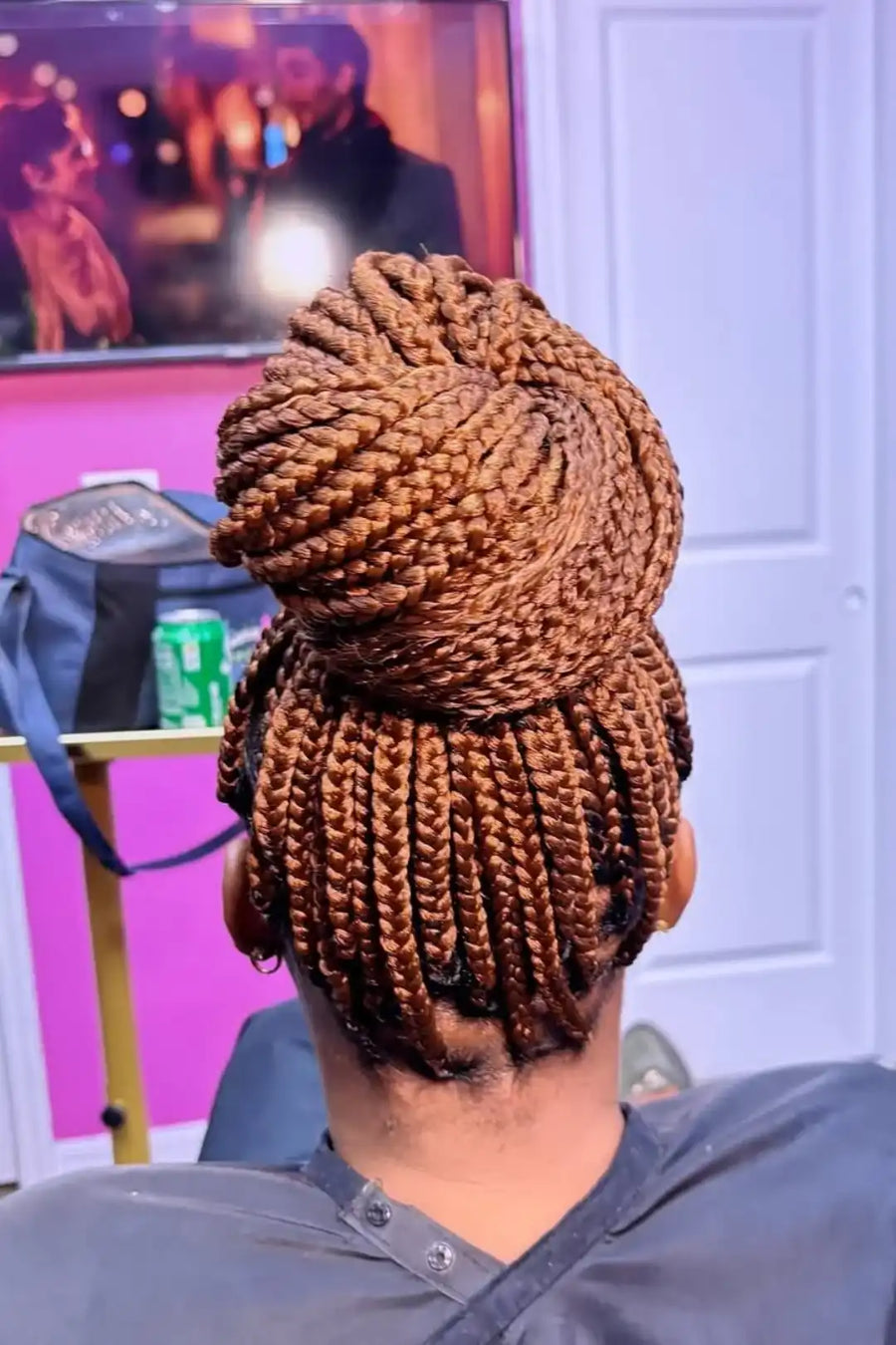 Person with braided hair sitting in a chair, with a blurred background