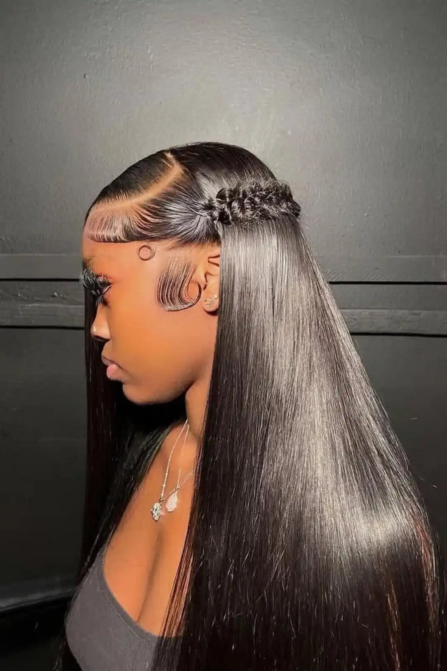 Person with long straight hair styled in a side part against a dark background