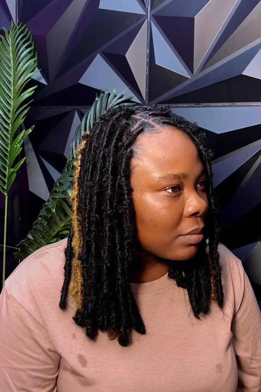 Woman with braided hair against a geometric-patterned wall