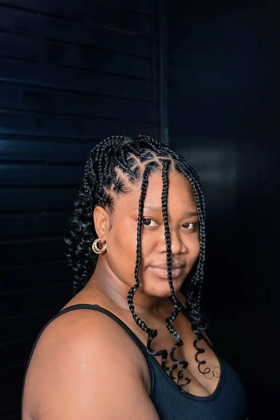 Woman with braided hair against a dark background