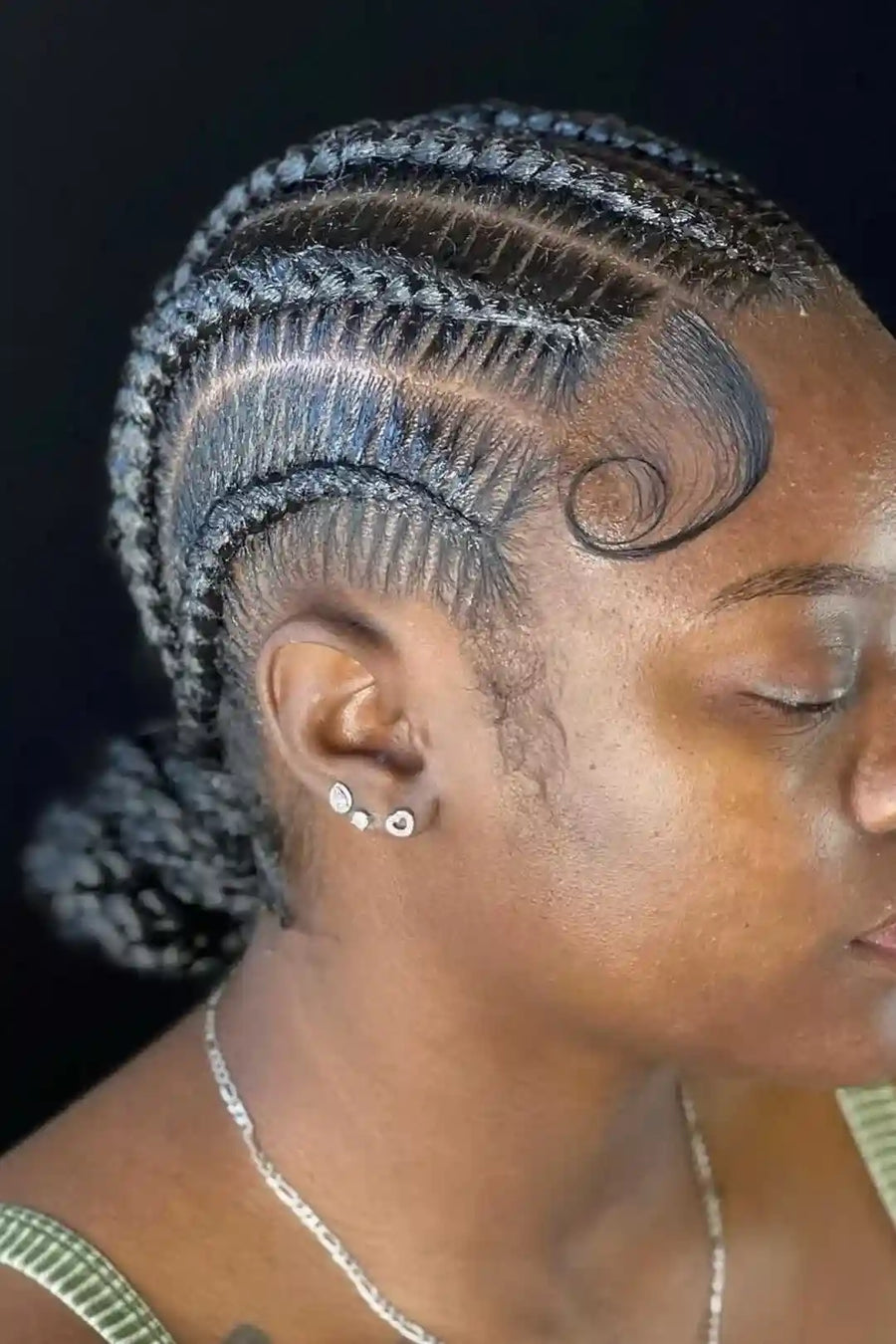 Woman with intricate braided hairstyle against a dark background