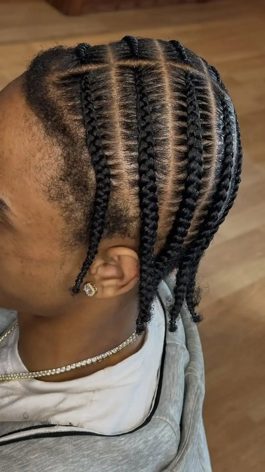 Person with styled braids on a wooden floor