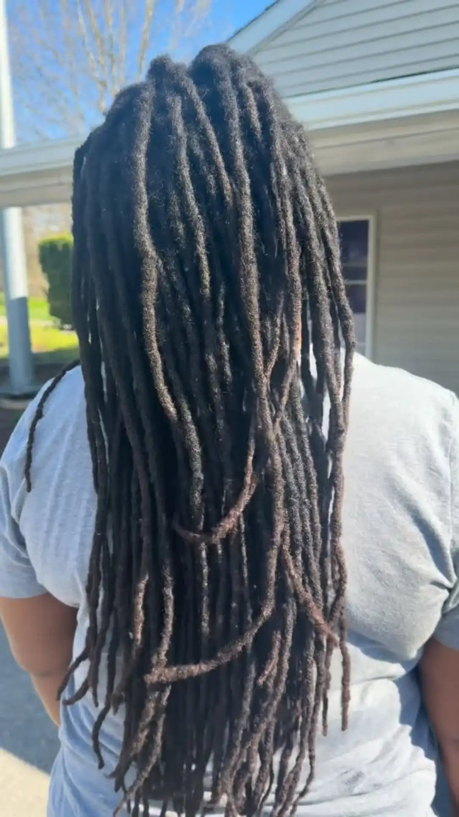 Person with long braided hair standing outdoors.