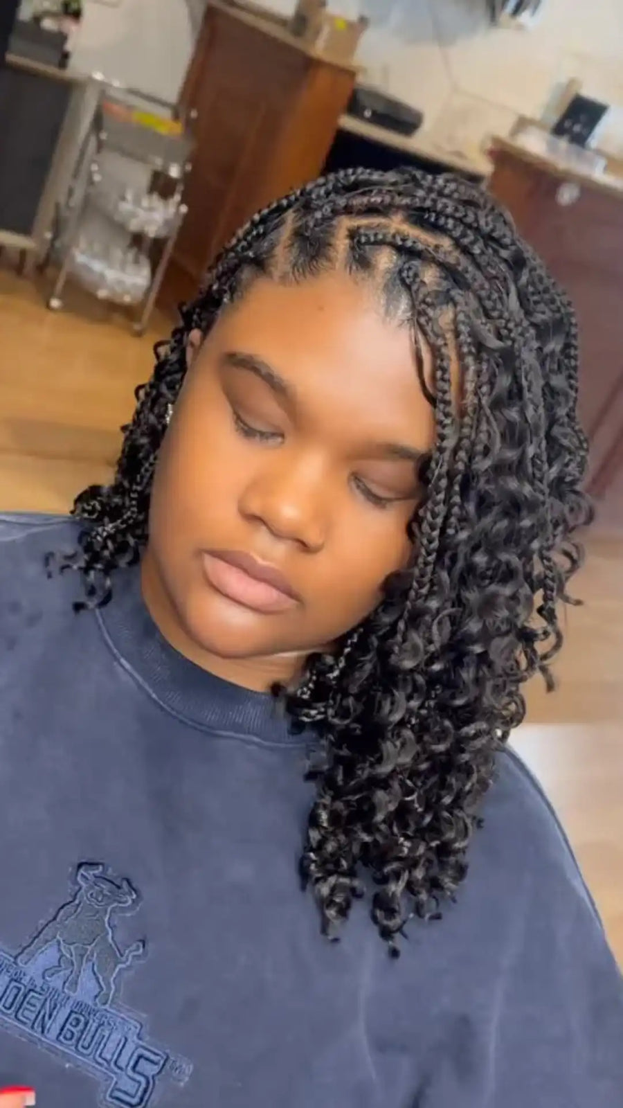 Person with styled hair wearing a blue sweatshirt in an indoor setting