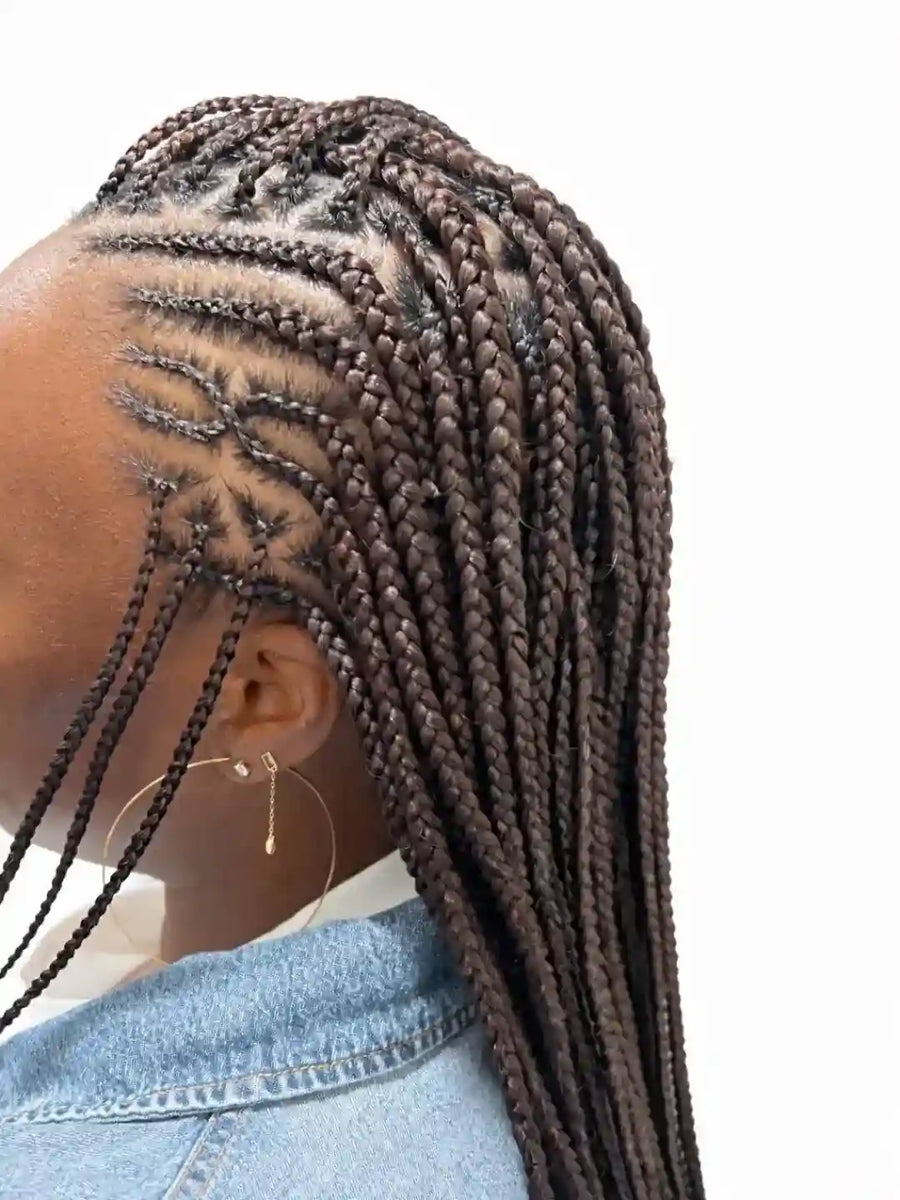 Person with braided hair wearing a denim jacket on a white background