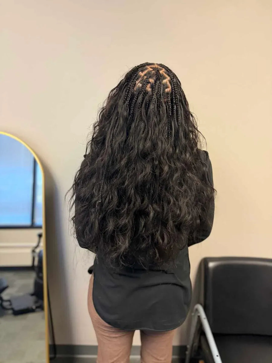 Person with long, styled hair in a room with a mirror and chair.