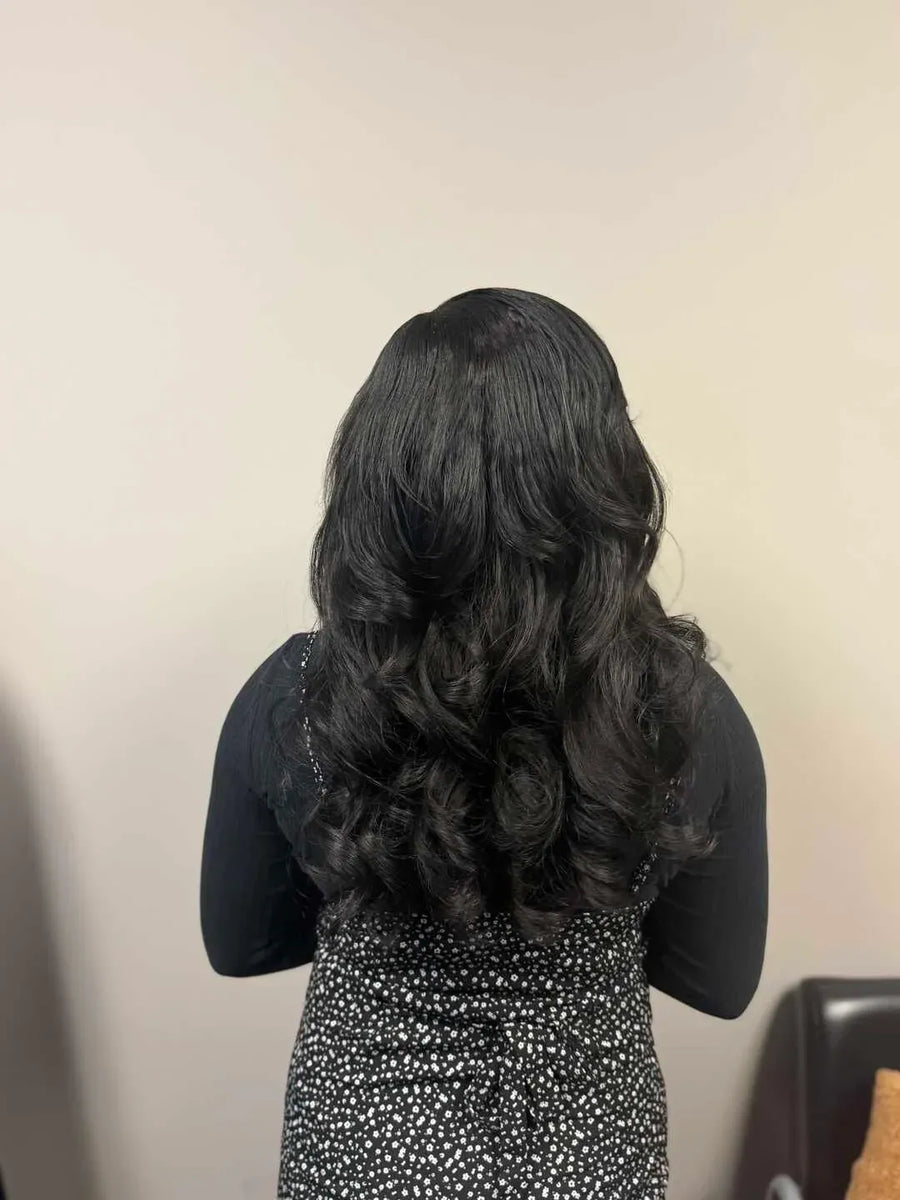 Person with long, wavy black hair against a plain background