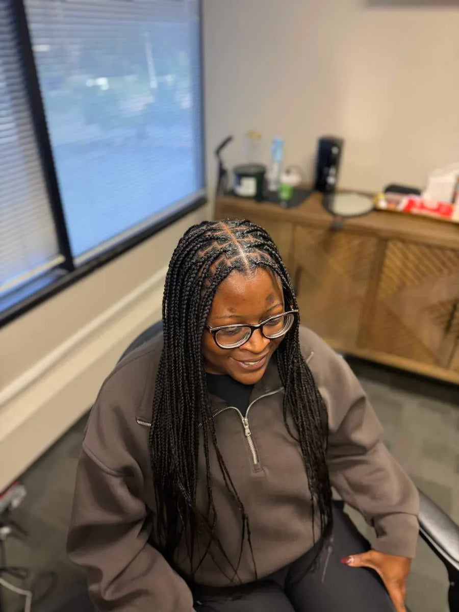 Person wearing glasses and a brown sweatshirt sitting in an office setting.