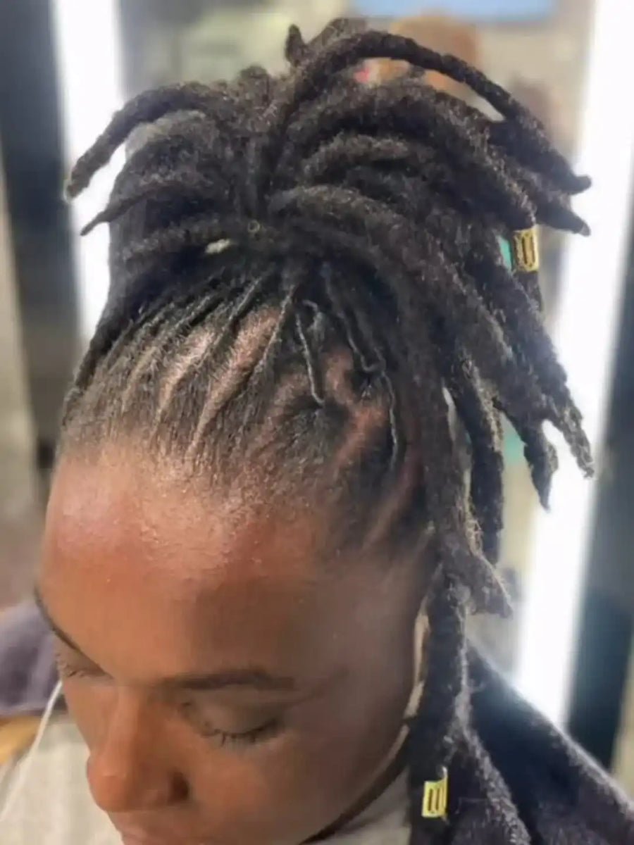 Close-up of a person with styled dreadlocks wearing a face mask.