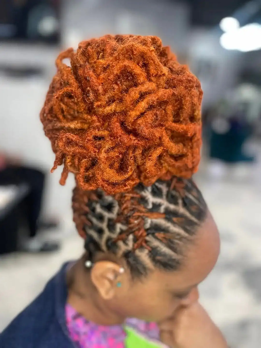 Person with braided hair styled into an intricate braid pattern, wearing a colorful garment.