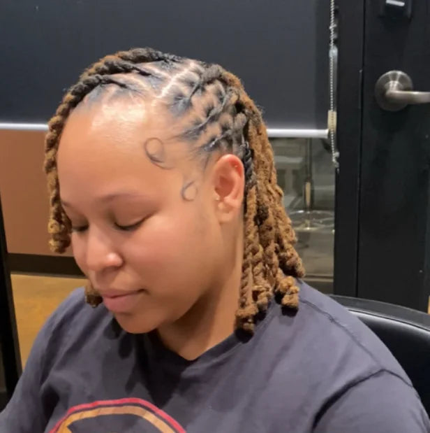 Person with braided hair wearing a dark blue shirt in an indoor setting