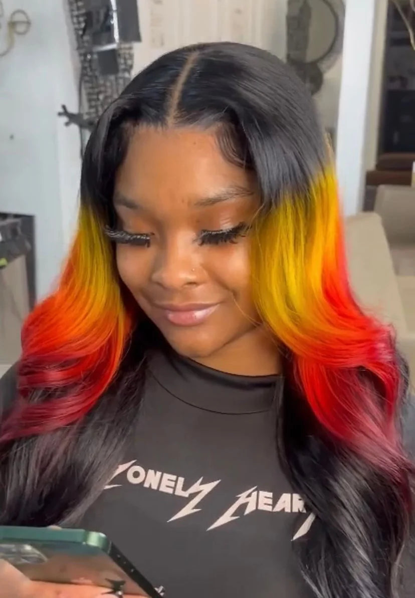 Person with colorful hair styled in a half-up, half-down look, wearing a black shirt with white text.