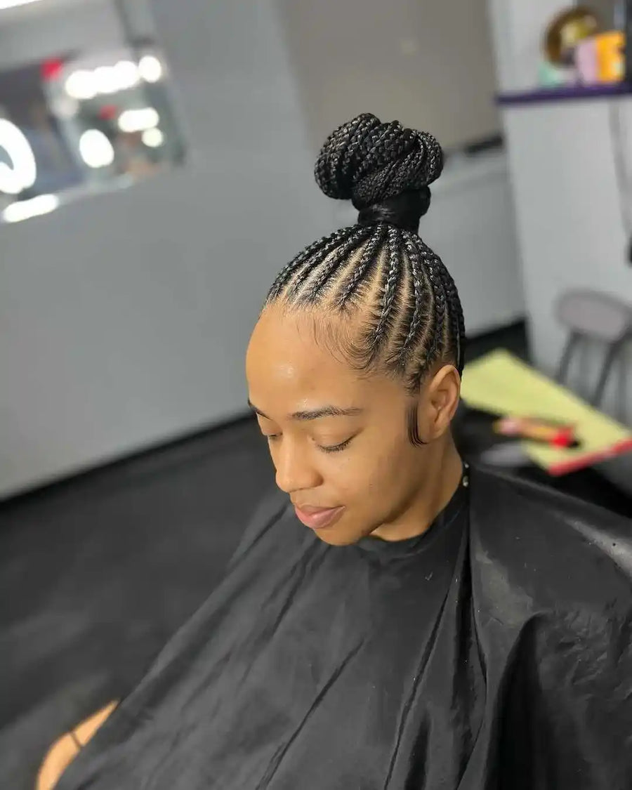 Person with braided hair sitting in a salon chair.