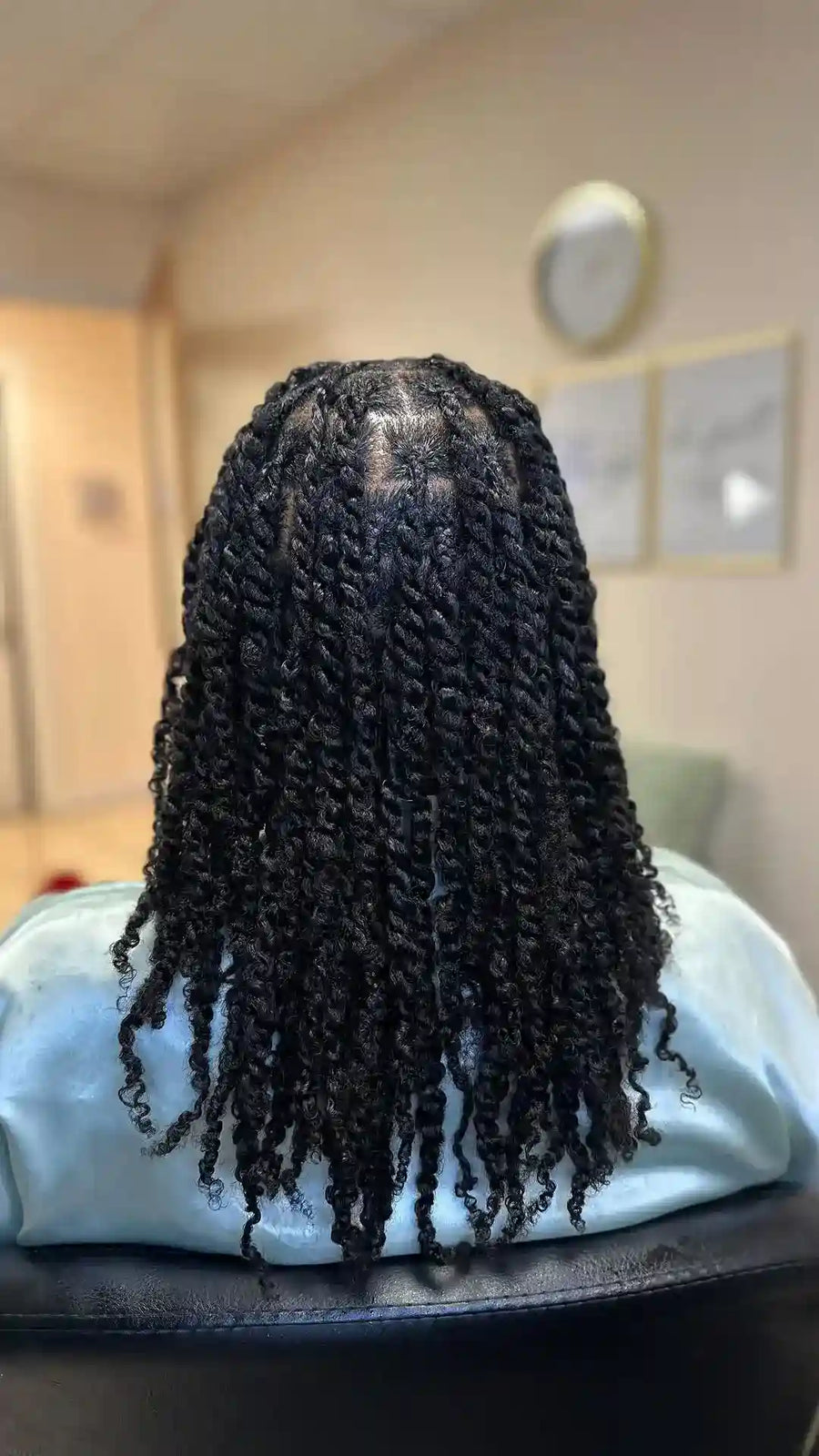Black braided wig on a mannequin head with a blurred indoor background
