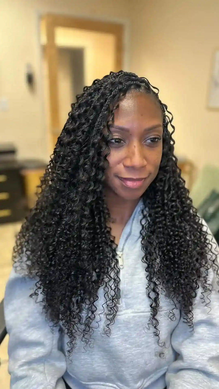 Woman with long, curly hair in a room with neutral walls.