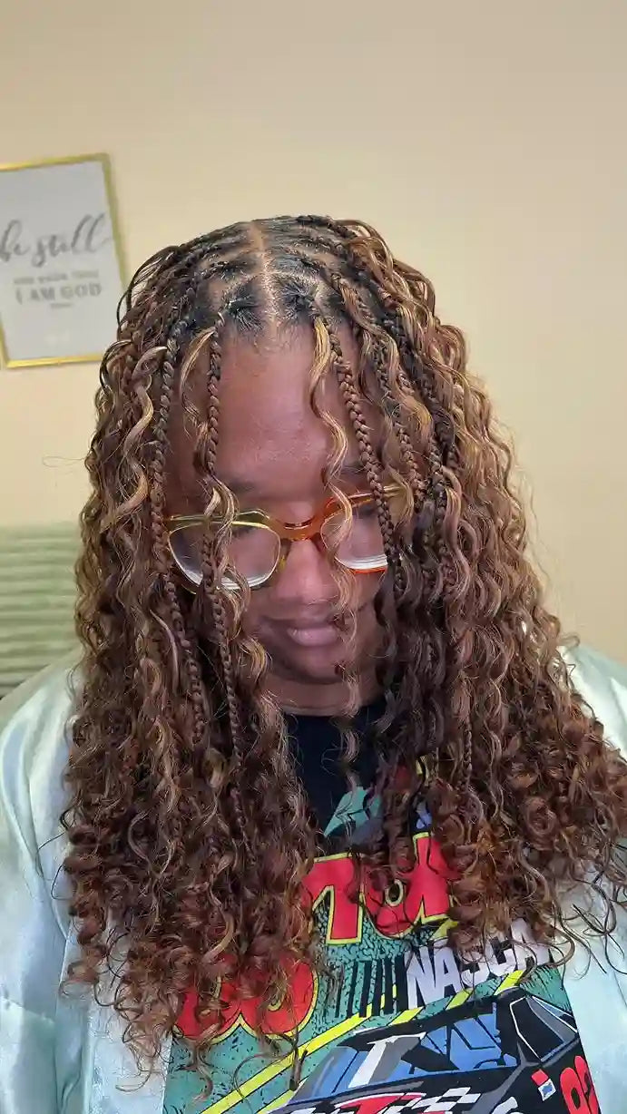 Person with long, braided hair wearing glasses indoors.
