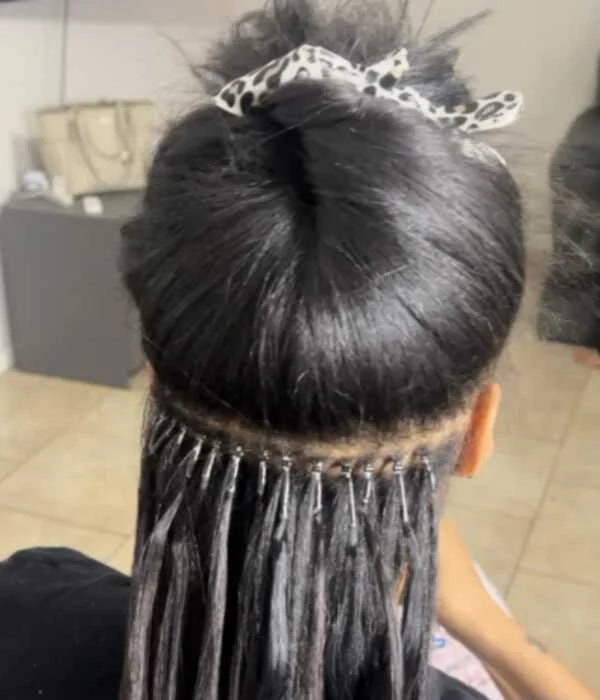 Person with a hair extension styled in a bun, with a blurred background.