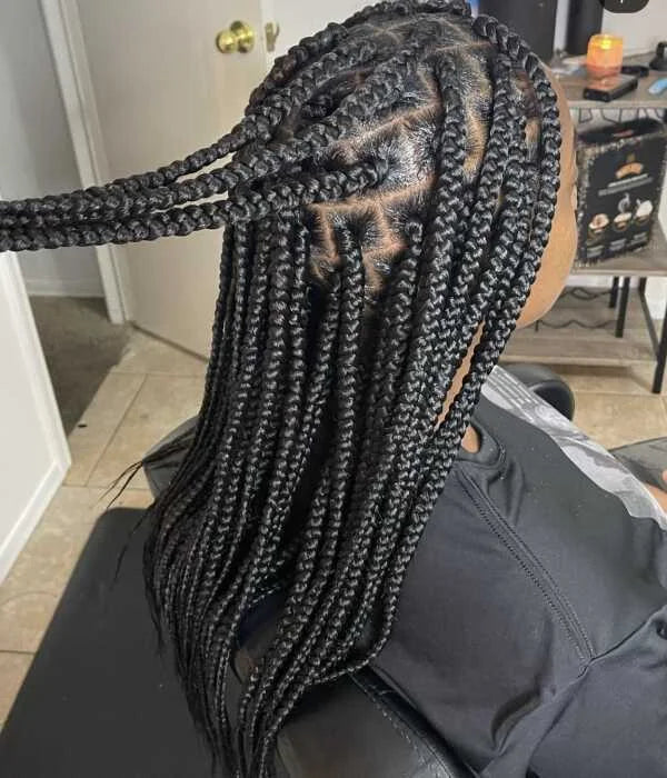 Person with braided hair sitting in a chair indoors.